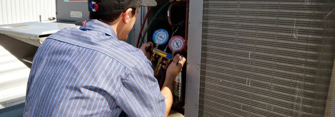 HVAC technician servicing a condenser unit in Anchorage