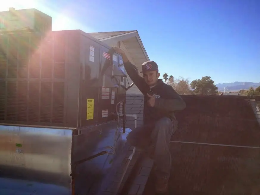 HVAC technician performing AC Tune-Up on a rooftop unit in Anchorage